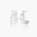 White gold plated sculptural hoop earrings with organic wavy edges and reflective metallic finish on cream background
