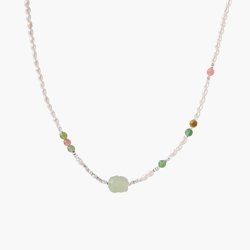 Delicate pearl necklace with pale green serpentine jade centerpiece and colorful agate beads on cream background