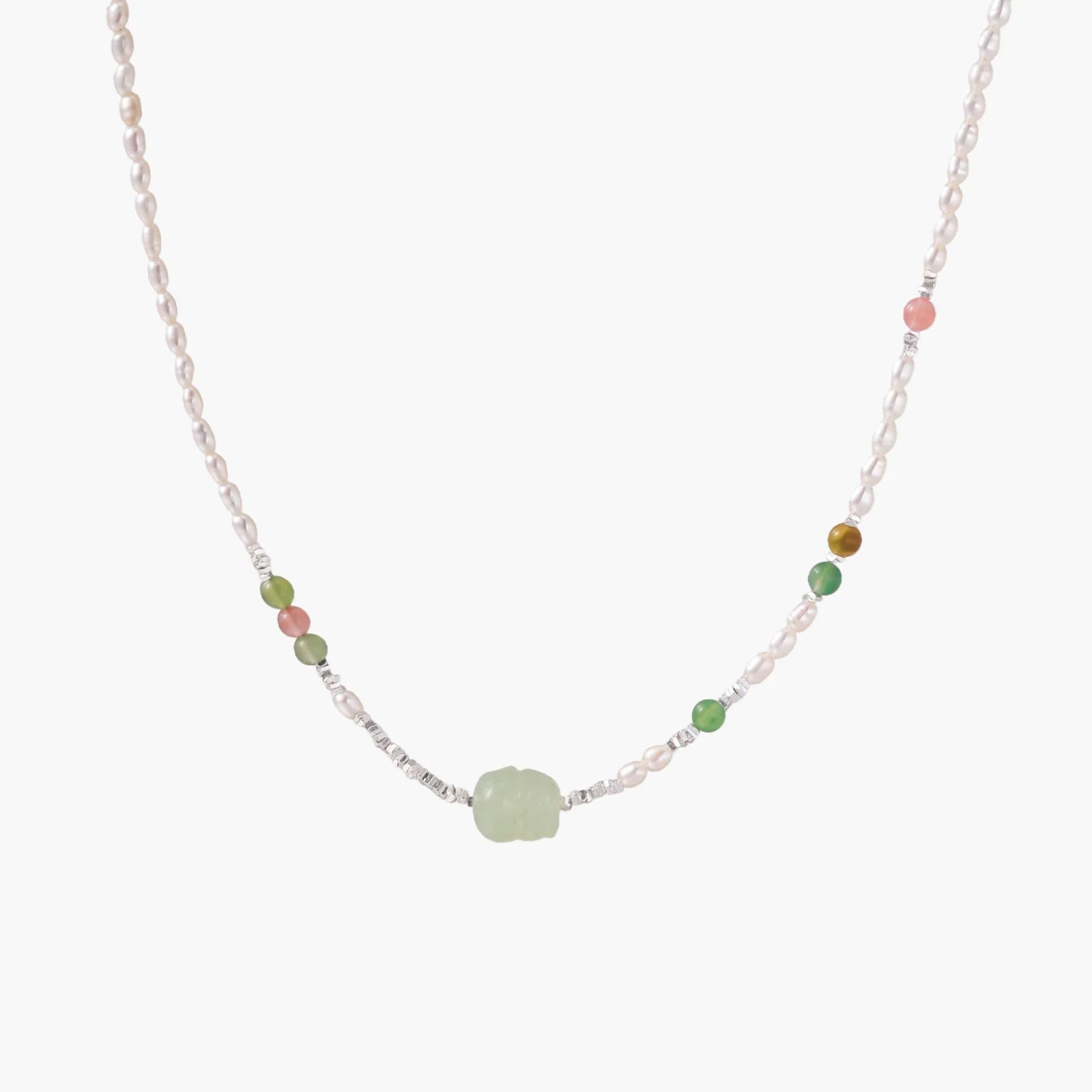 Delicate pearl necklace with pale green serpentine jade centerpiece and colorful agate beads on cream background
