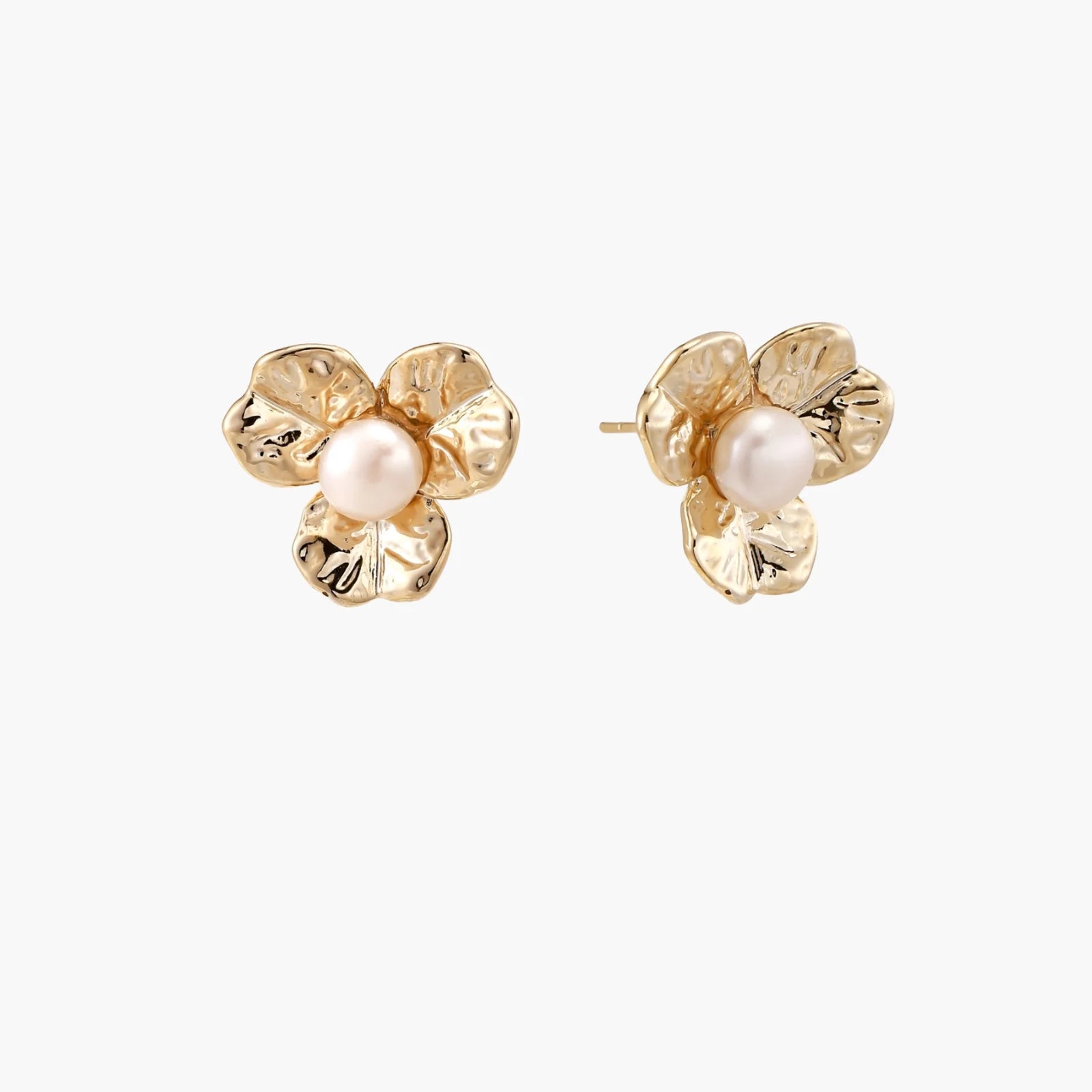 Gold-plated flower stud earrings with textured petals and centered freshwater pearl on beige background
