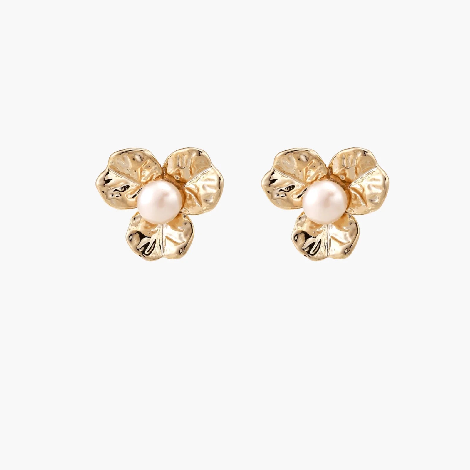 Gold-plated flower stud earrings with textured petals and centered freshwater pearl on beige background