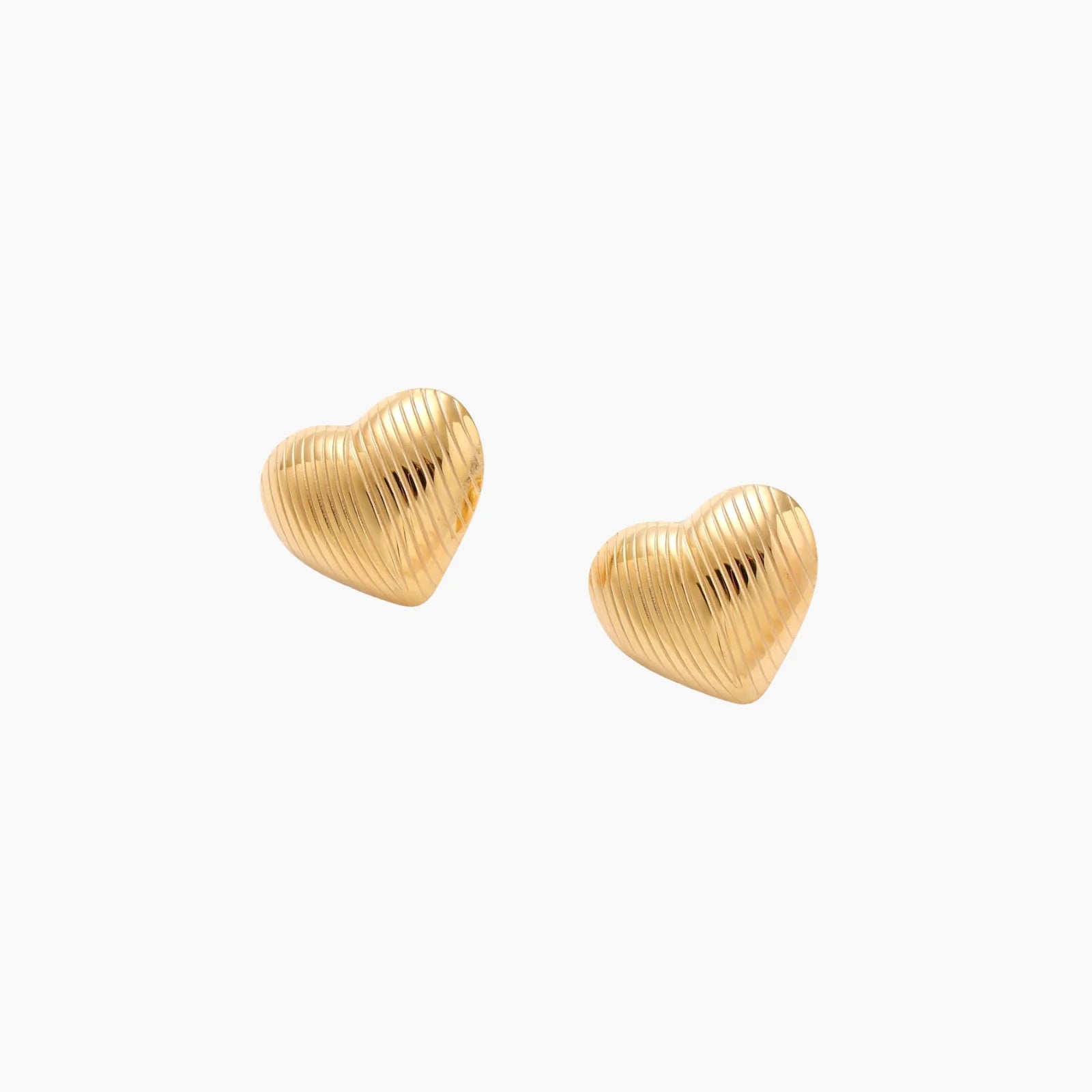 Gold heart-shaped stud earrings with parallel ridged texture on cream background