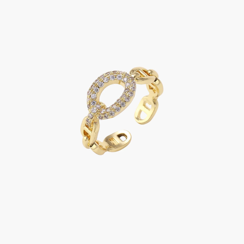 Gold-plated brass chain link ring with one oval CZ-pavé segment on cream background, adjustable cuff style.