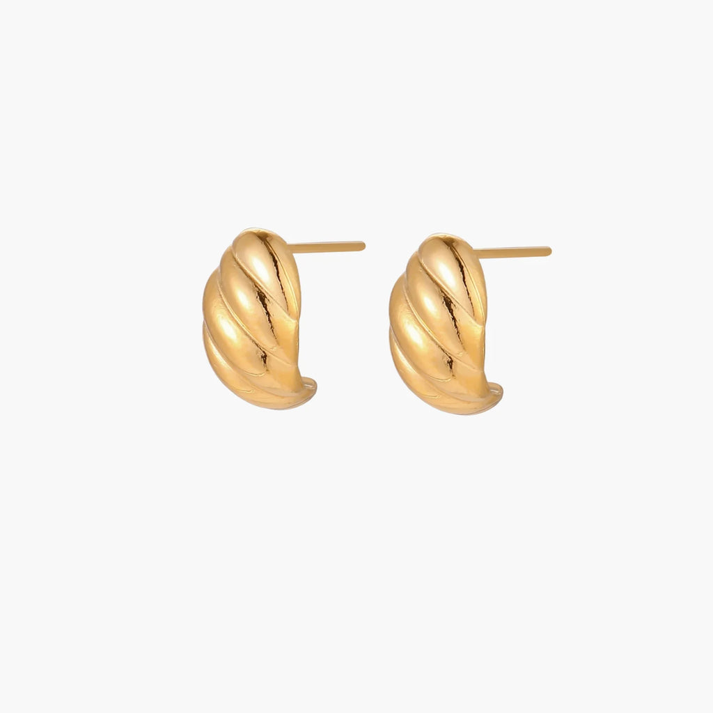 Chunky gold twisted rope huggie hoops with diagonal grooves and high-polish finish on cream background