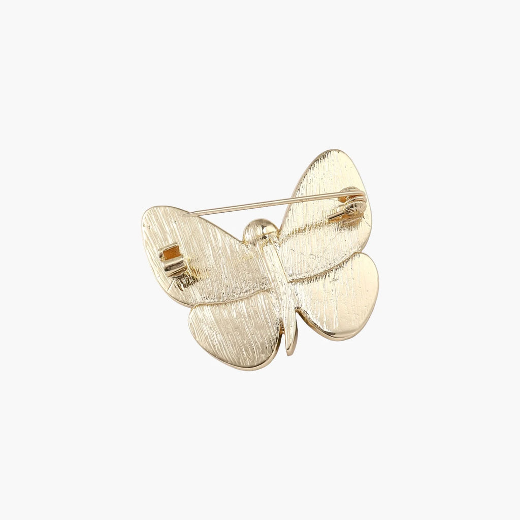 Gold-plated butterfly brooch with iridescent abalone shell wings and freshwater pearl accent on cream background.
