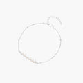 Delicate rhodium-plated silver chain bracelet with row of small baroque pearls centered on white background.