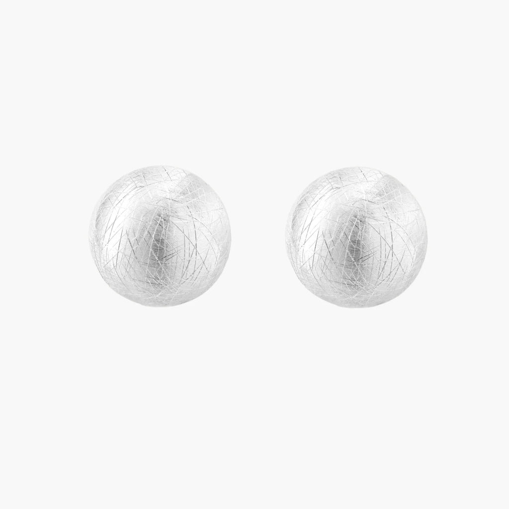 Brushed sterling silver half-dome clip-on earrings with textured surface against cream background