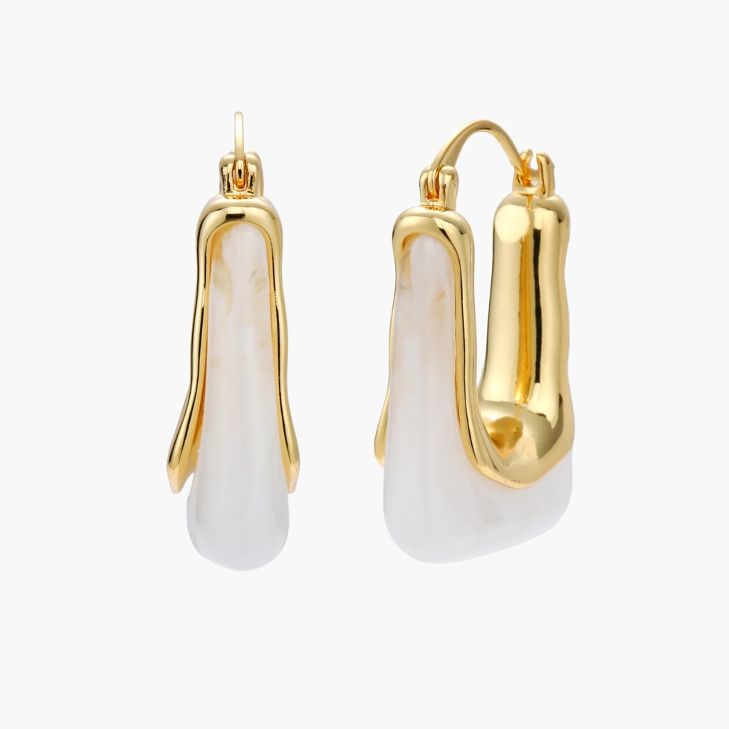 Sculptural gold-plated hoop earrings with flowing curved design and lever-back closure on cream background.