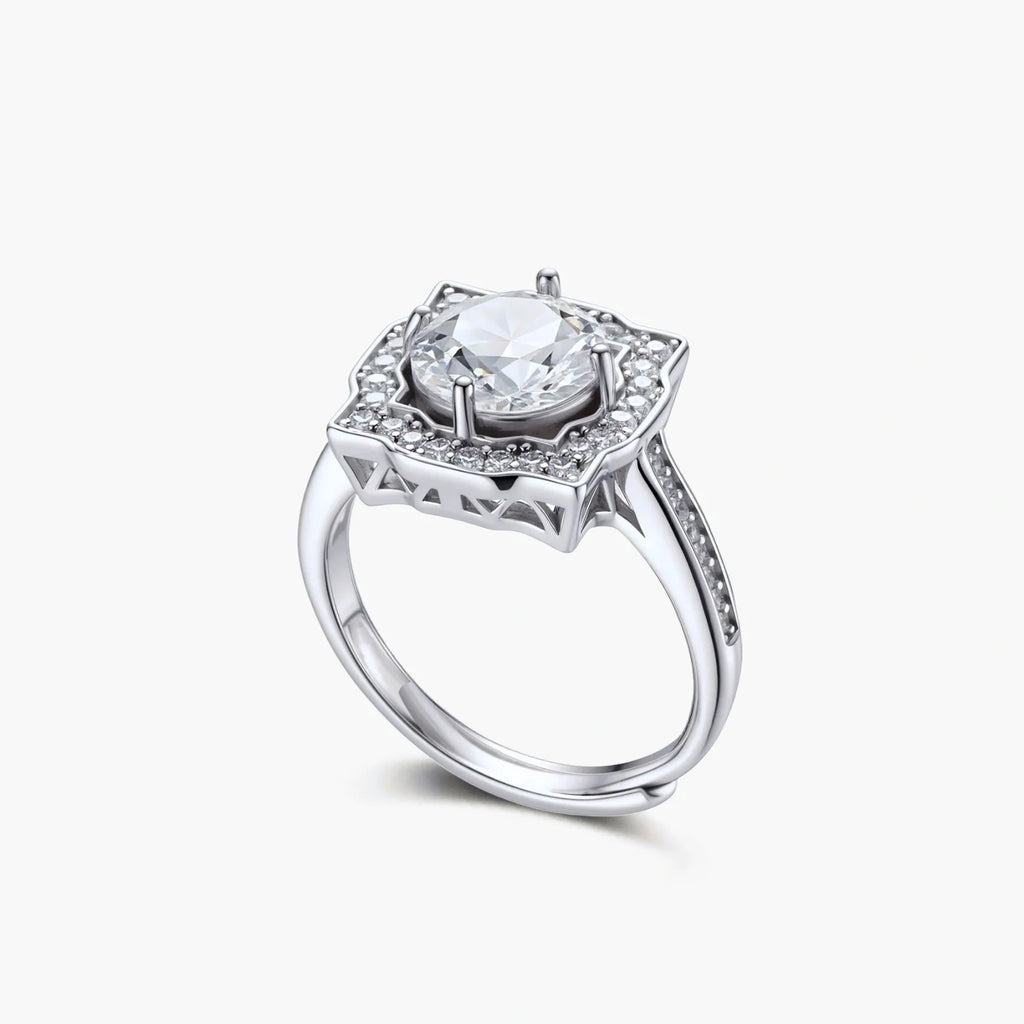 Sterling silver ring with round moissanite center stone in ornate scalloped halo setting on white background.