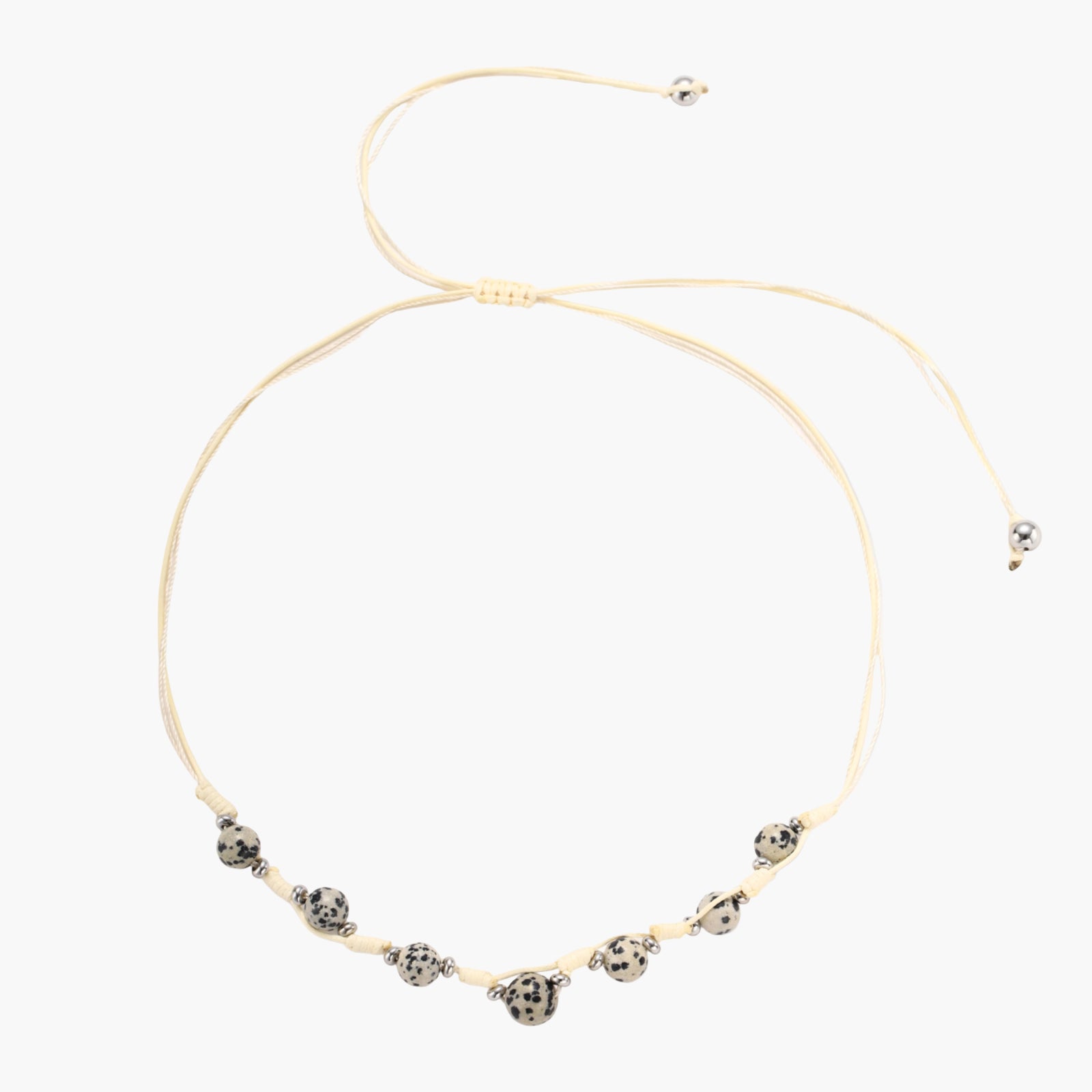 Adjustable cream cord necklace with white spotted stone beads featuring black speckles on neutral background