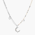 Silver-toned crescent moon pendant with star accents on pearl and chain necklace against white background.