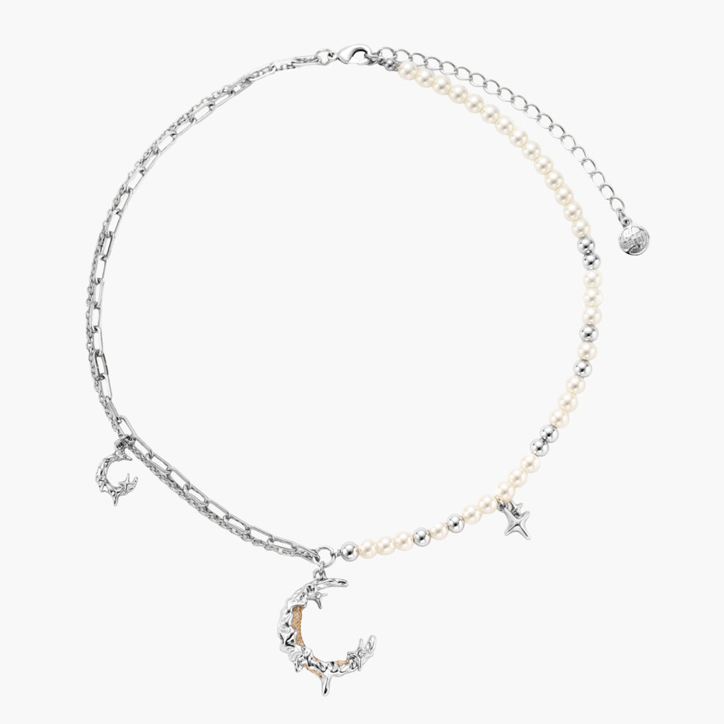 Silver-toned crescent moon pendant with star accents on pearl and chain necklace against white background.