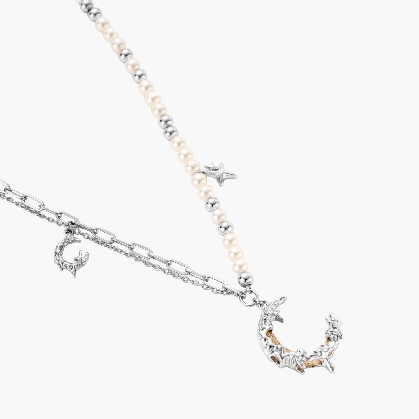 Silver-toned crescent moon pendant with star accents on pearl and chain necklace against white background.