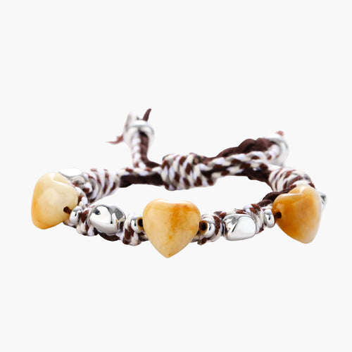 Braided brown and cream suede cord bracelet with heart-shaped amber gemstones and brass beads on white background.