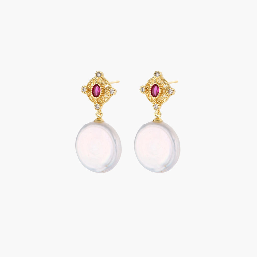 Gold baroque pearl earrings with pink gemstone studs and ornate detailing on cream background.