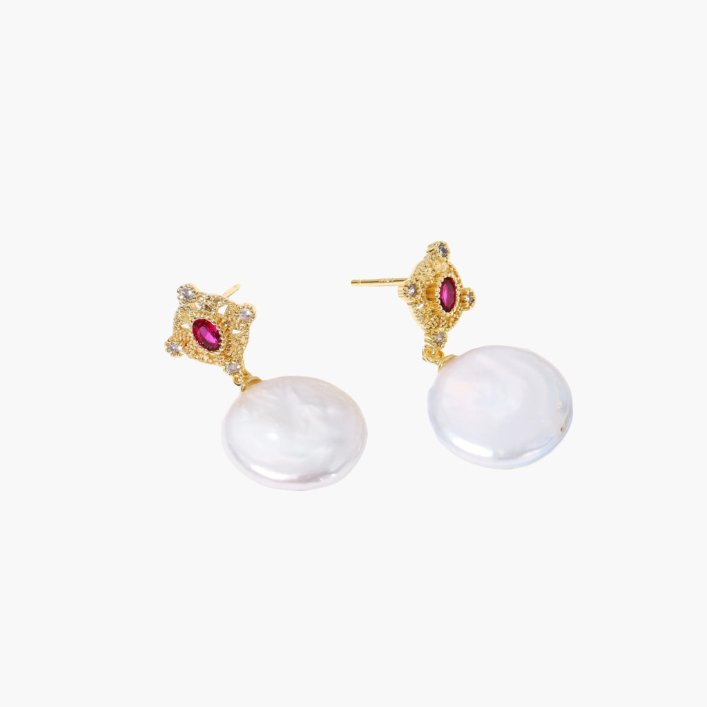 Gold baroque pearl earrings with pink gemstone studs and ornate detailing on cream background.