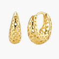 Close-up of small gold-plated hoop earrings with intricate honeycomb cutout pattern on cream background.