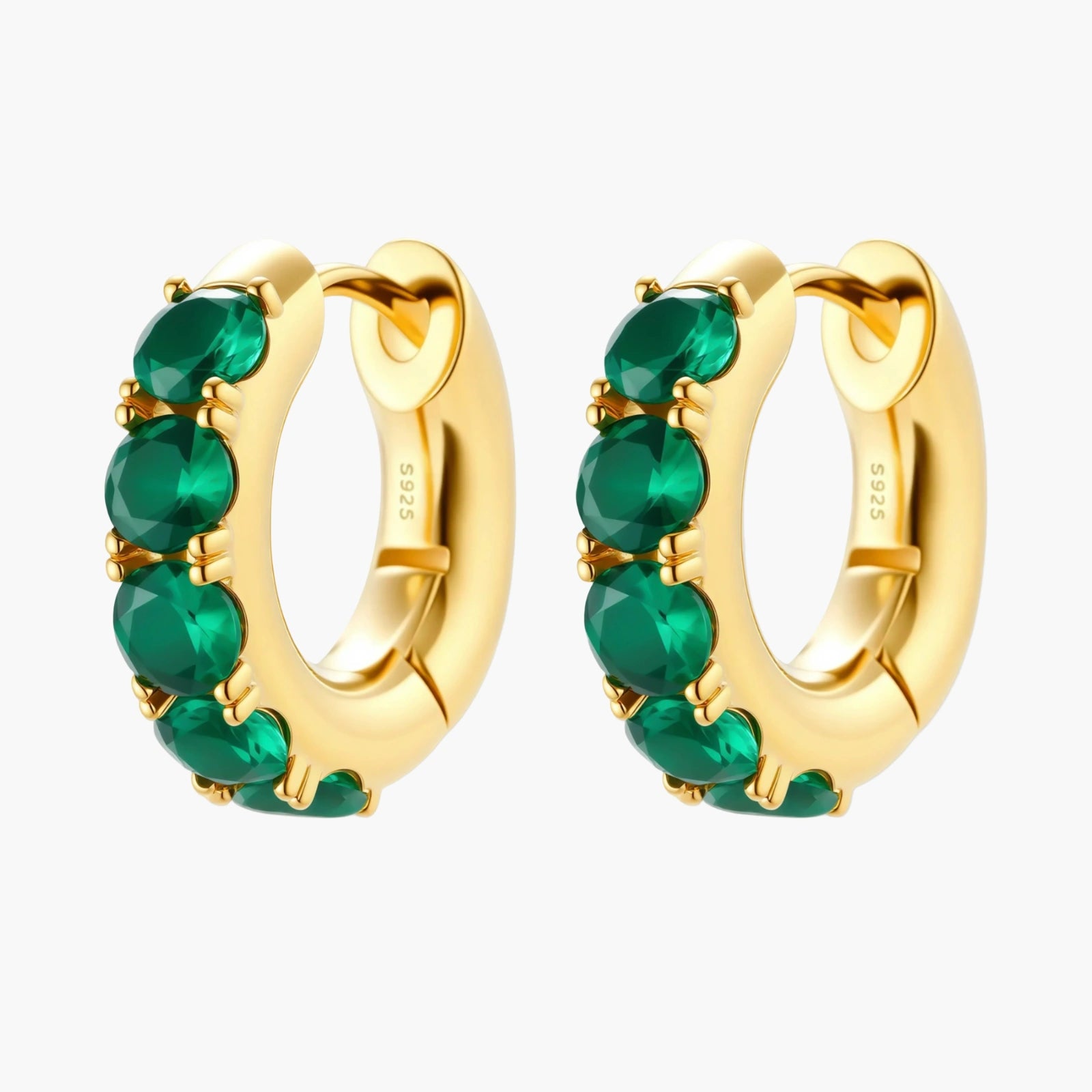 Close-up of gold-plated huggie hoop earrings featuring four emerald green cubic zirconia stones on white background.