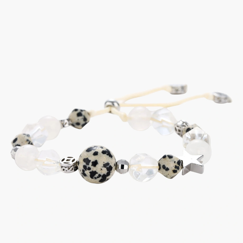 Adjustable beaded bracelet with spotted dalmatian stones, clear quartz crystals, and silver star charm on white background.