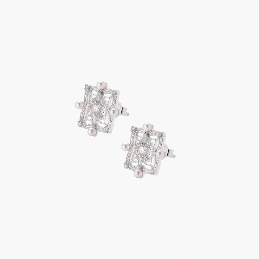 Ornate sterling silver stud earrings with mandala-inspired filigree pattern and four freshwater pearls on beige background