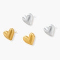 Pair of textured heart-shaped stud earrings in brushed platinum-plated sterling silver against cream background.
