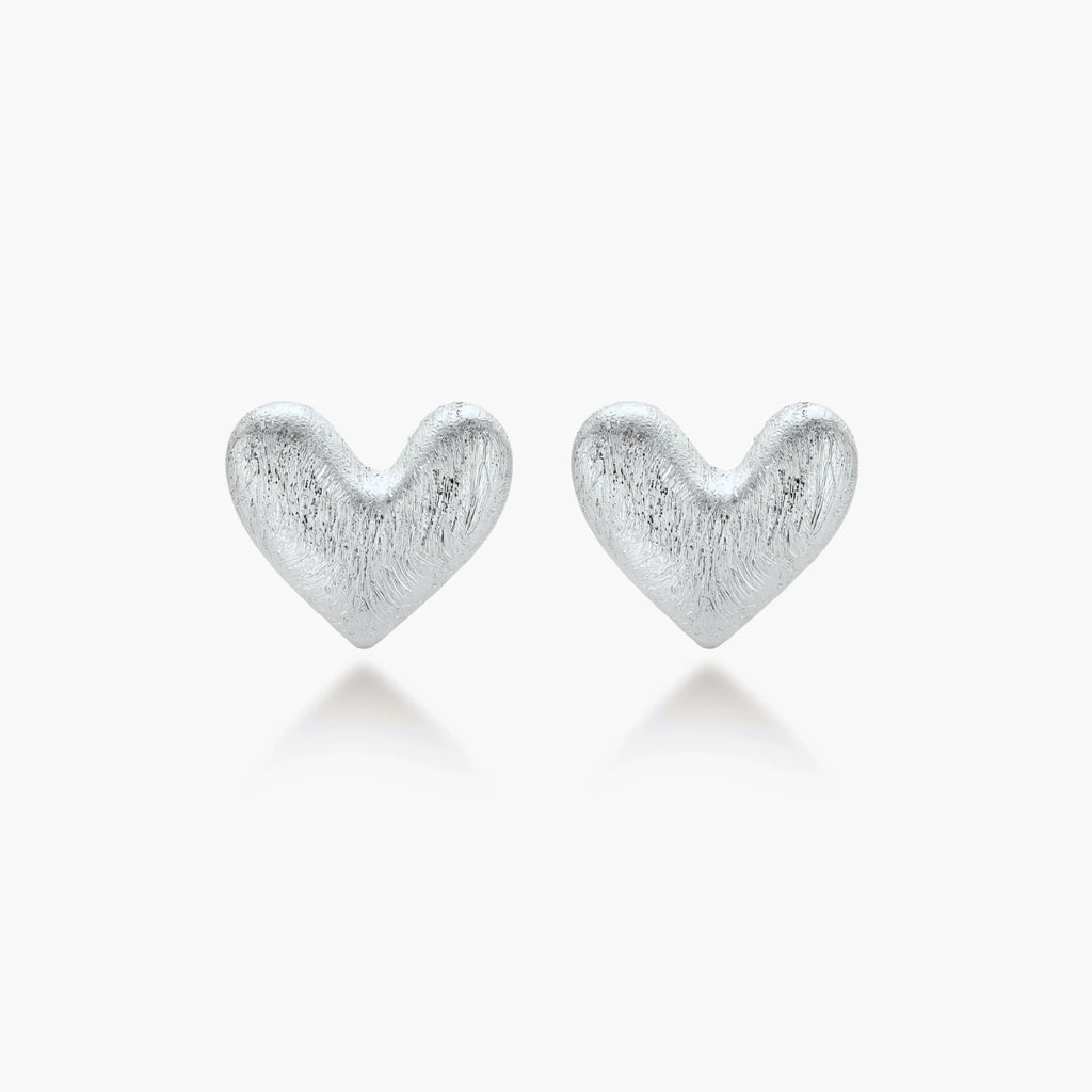 Pair of brushed platinum-plated 925 sterling silver puffy heart stud earrings on a cream background.