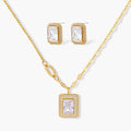 Gold-plated jewelry set with rectangular cubic zirconia stones in pave halo settings on cream background