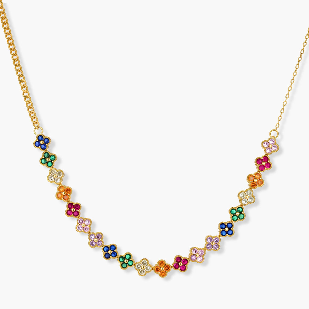 Colorful four-leaf clover jewelry set with rainbow cubic zirconia stones in gold-plated setting on white background