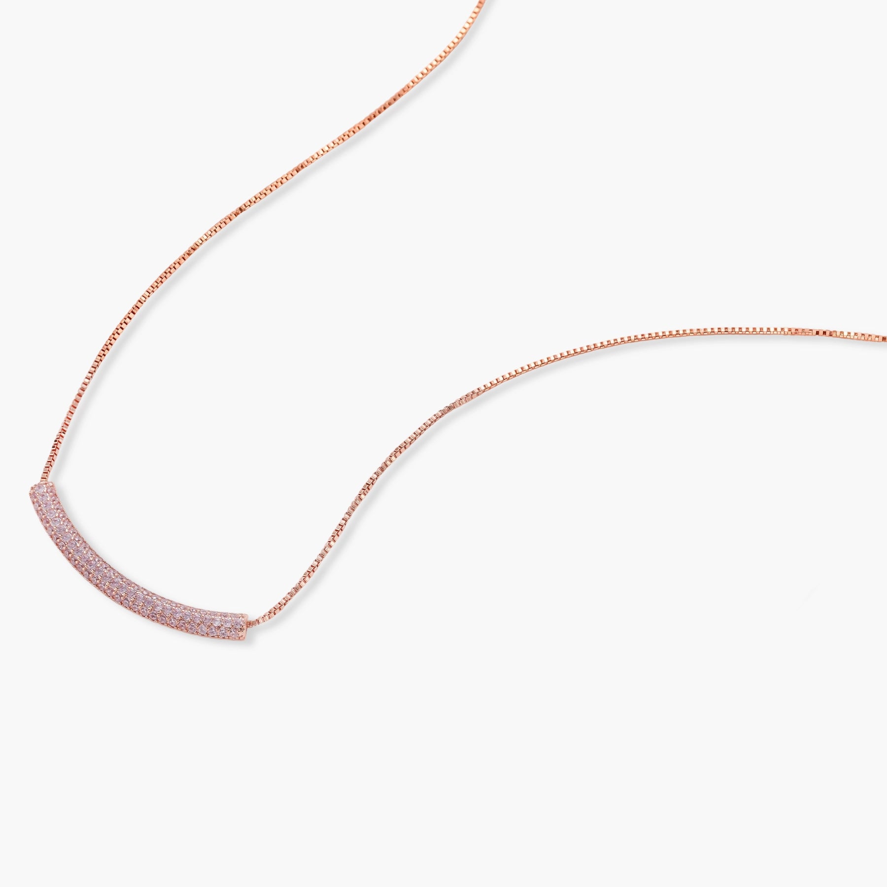 Rose gold jewelry set with pavé cubic zirconia stones including curved necklace, hoop earrings, and adjustable ring on cream background.